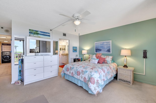 bedroom with a textured ceiling, ensuite bathroom, washer / clothes dryer, ceiling fan, and light carpet