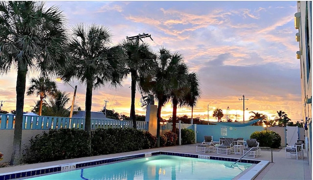 pool at dusk featuring a patio