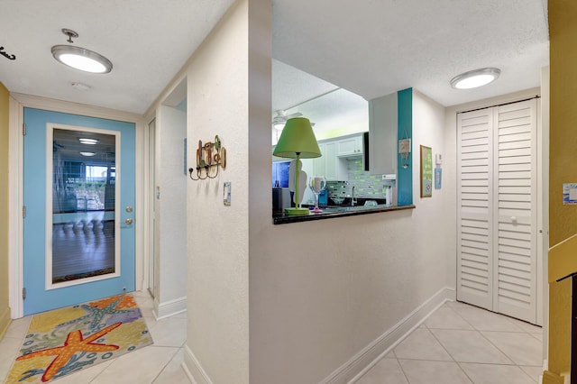 corridor featuring a textured ceiling and light tile patterned floors