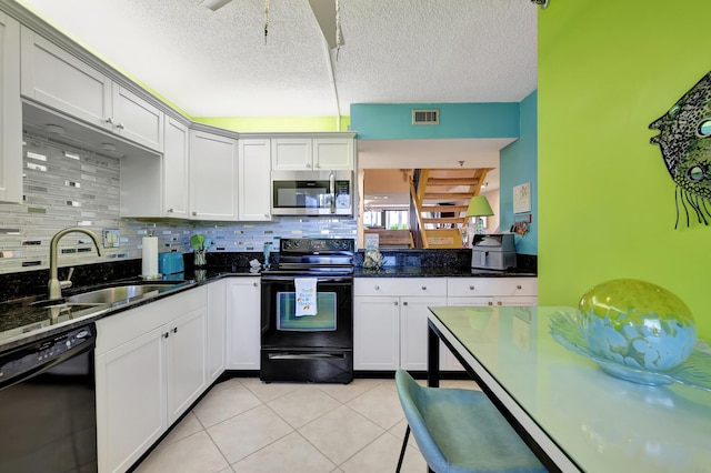 kitchen with black appliances, light tile patterned floors, white cabinetry, dark stone counters, and sink