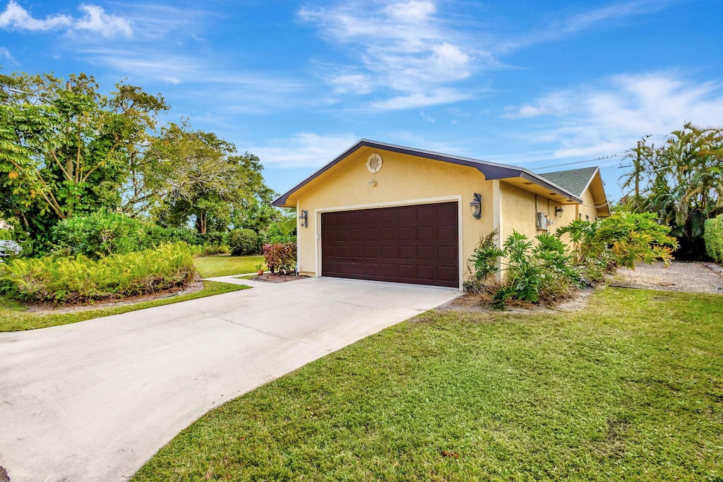 single story home with a garage and a front lawn