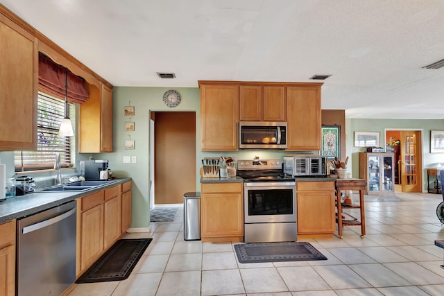 kitchen featuring light tile patterned flooring, appliances with stainless steel finishes, a kitchen bar, and sink