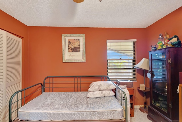 carpeted bedroom with a textured ceiling and a closet