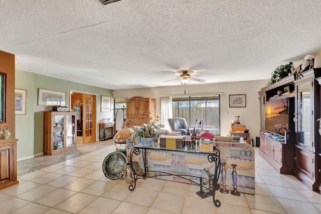 living room with ceiling fan, light tile patterned floors, and a textured ceiling