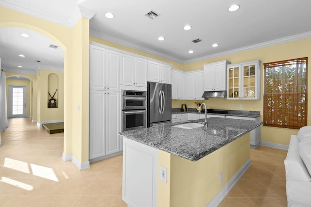 kitchen with dark stone counters, sink, light tile patterned floors, white cabinetry, and stainless steel appliances