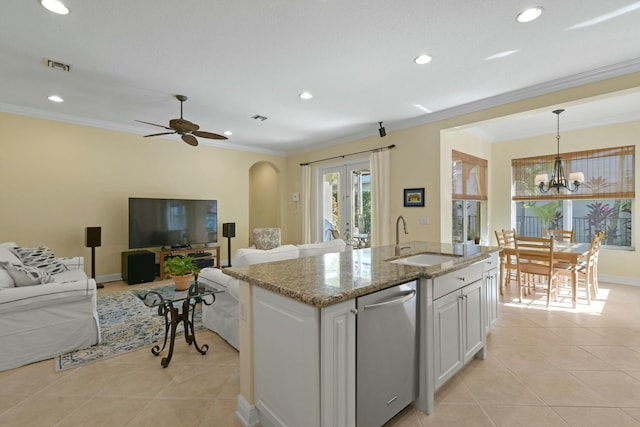 kitchen featuring stainless steel dishwasher, sink, pendant lighting, white cabinets, and an island with sink