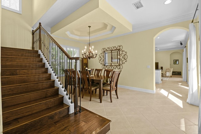 dining room featuring a notable chandelier, a raised ceiling, ornamental molding, and light tile patterned floors