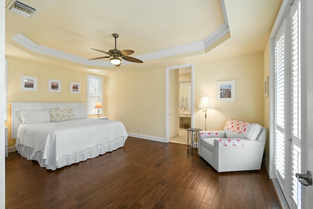 bedroom with connected bathroom, ceiling fan, dark hardwood / wood-style floors, a tray ceiling, and ornamental molding