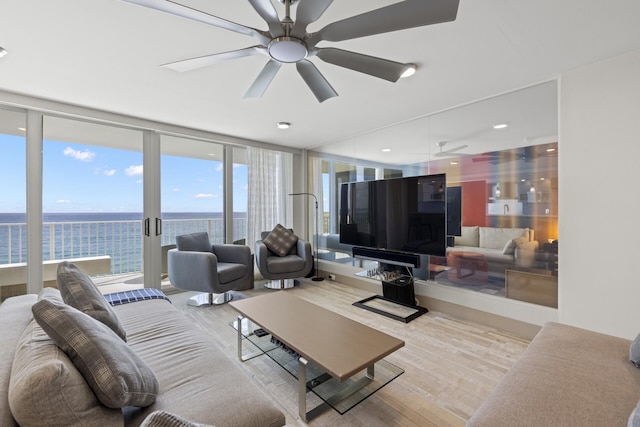 living room with ceiling fan, light hardwood / wood-style floors, and a wall of windows