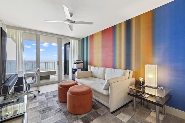 living room with expansive windows, ceiling fan, and a water view