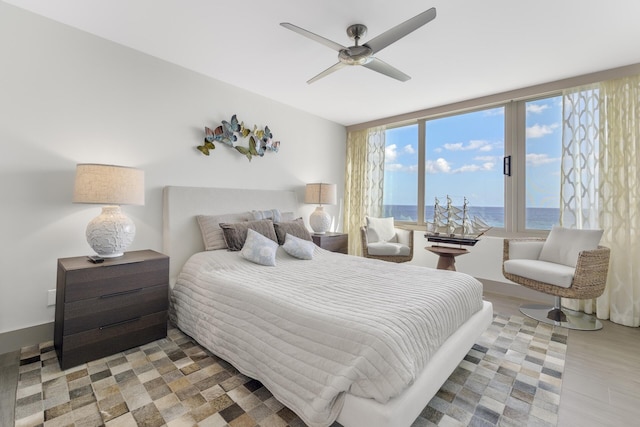 bedroom featuring hardwood / wood-style floors, ceiling fan, and a water view