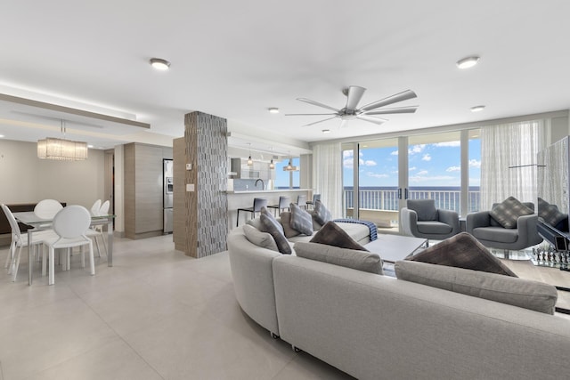 living room with expansive windows and ceiling fan with notable chandelier