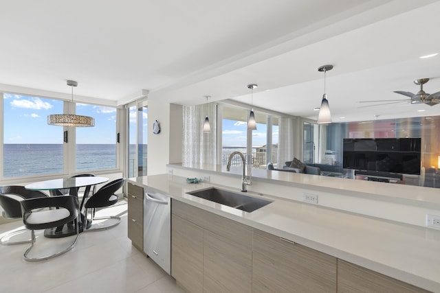 kitchen featuring sink, stainless steel dishwasher, hanging light fixtures, and a water view