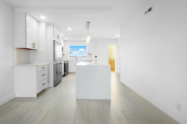 kitchen featuring range, sink, decorative light fixtures, white cabinetry, and stainless steel refrigerator