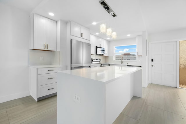 kitchen featuring a center island, stainless steel appliances, an inviting chandelier, pendant lighting, and white cabinets