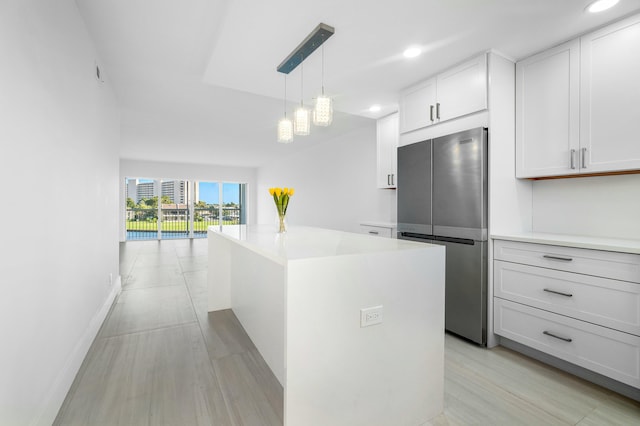 kitchen with white cabinetry, hanging light fixtures, an inviting chandelier, stainless steel fridge, and a kitchen island