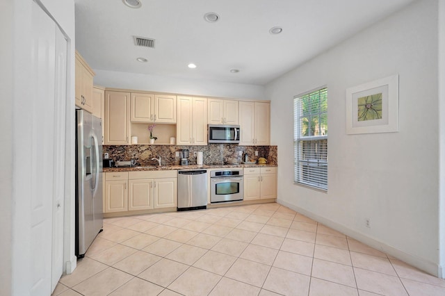 kitchen featuring stone counters, sink, backsplash, light tile patterned flooring, and appliances with stainless steel finishes