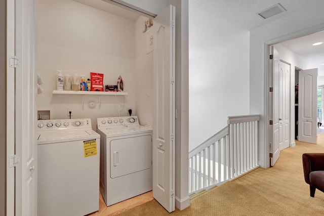 laundry room featuring washer and clothes dryer and light colored carpet