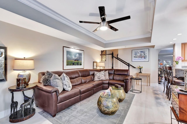 living room featuring ceiling fan, a tray ceiling, and crown molding