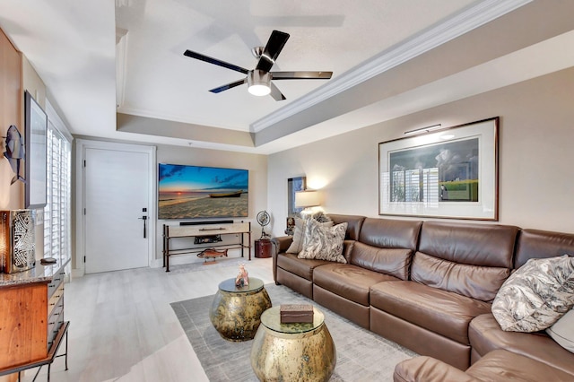 living room with ornamental molding, a raised ceiling, ceiling fan, and light hardwood / wood-style floors