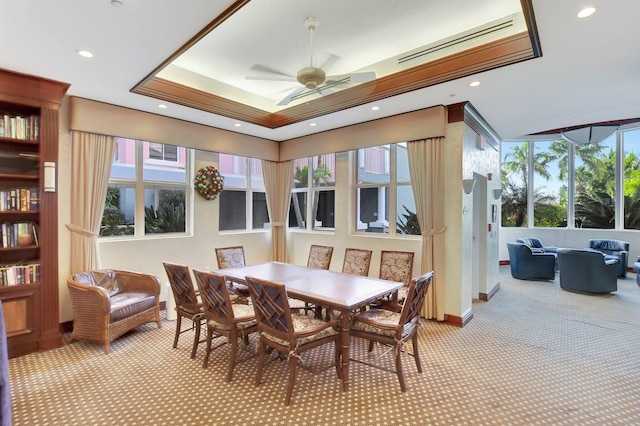 carpeted dining room featuring ceiling fan, ornamental molding, and a raised ceiling