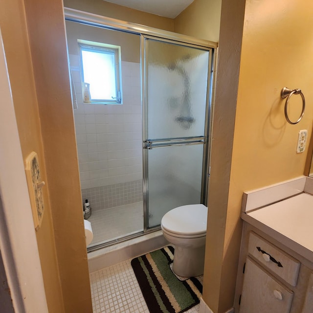 bathroom featuring tile patterned flooring, vanity, toilet, and a shower with shower door