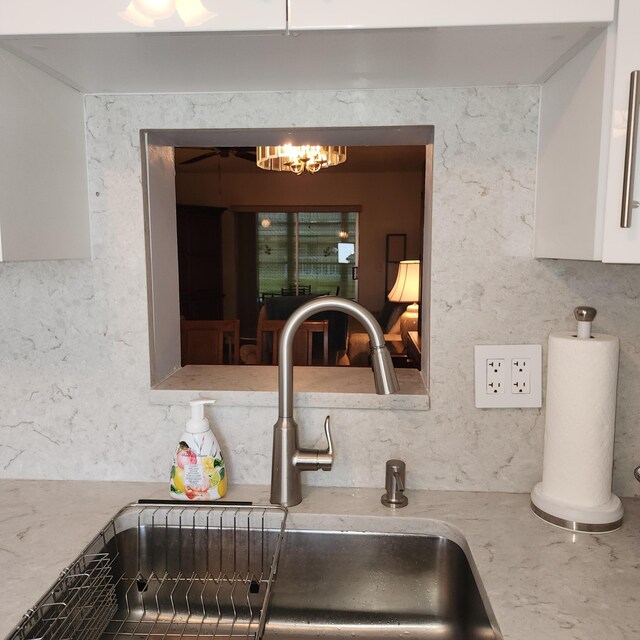 room details with backsplash, sink, and white cabinets