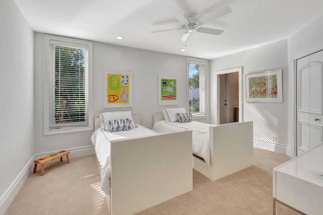 carpeted bedroom featuring ceiling fan, multiple windows, and a closet