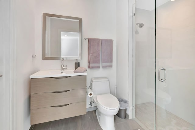 bathroom with a shower with door, vanity, and toilet