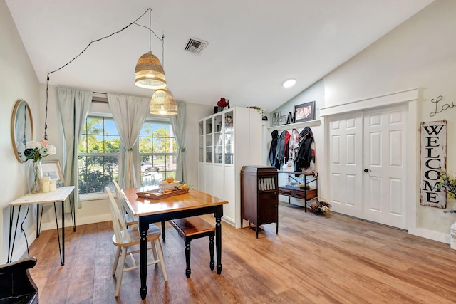 dining space with light hardwood / wood-style floors and vaulted ceiling