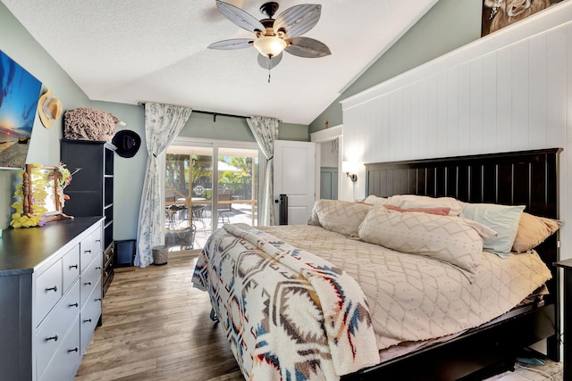 bedroom with a textured ceiling, access to outside, vaulted ceiling, ceiling fan, and hardwood / wood-style flooring