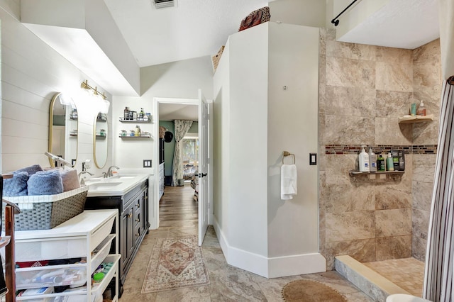 bathroom with tiled shower and vanity