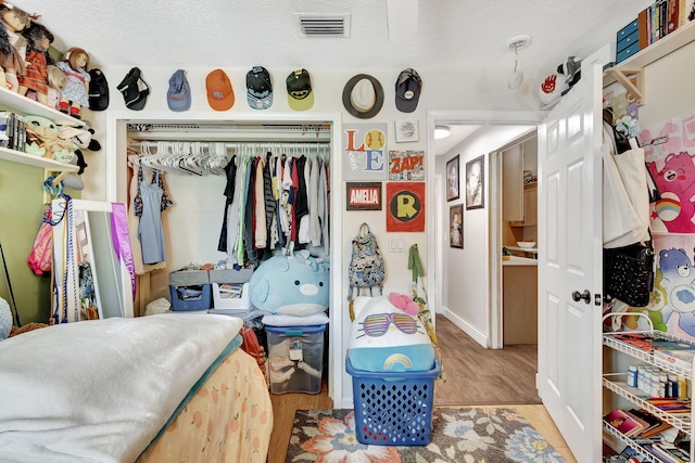 bedroom with a closet, a textured ceiling, and light hardwood / wood-style flooring