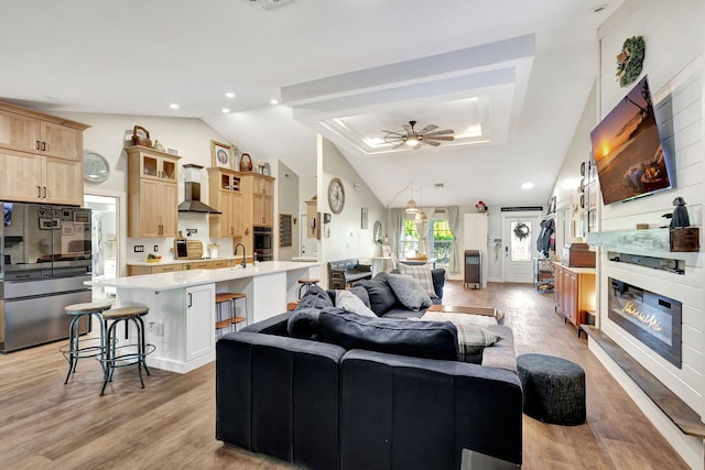 living room with light wood-type flooring, ceiling fan, lofted ceiling, and sink