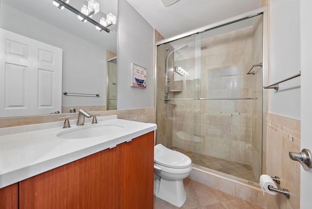 bathroom with tile patterned flooring, toilet, a shower with shower door, and tile walls