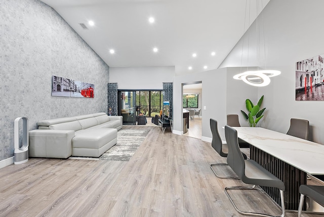 living room featuring light wood-type flooring, high vaulted ceiling, and an inviting chandelier