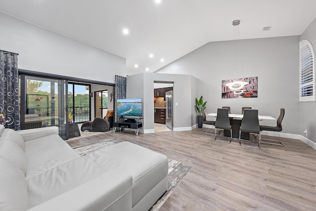 living room featuring light hardwood / wood-style floors and high vaulted ceiling