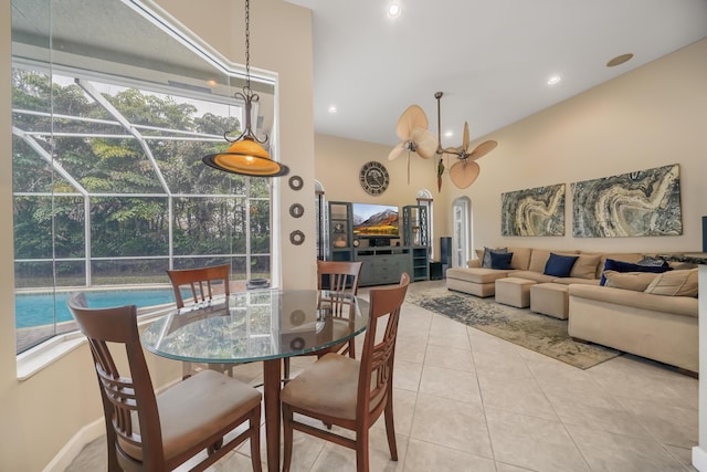 dining space featuring arched walkways, a towering ceiling, a sunroom, tile patterned floors, and recessed lighting