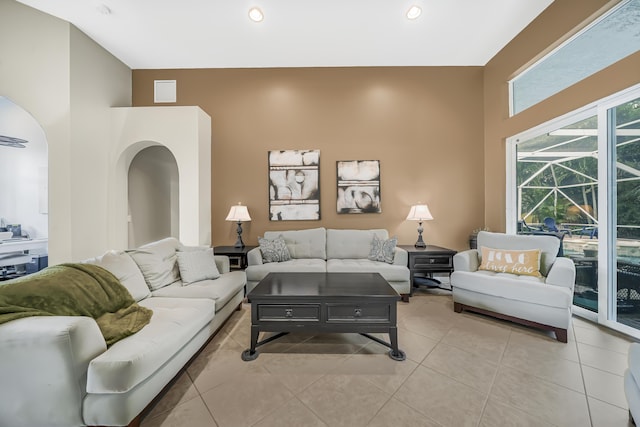 living area featuring light tile patterned floors, arched walkways, a sunroom, and recessed lighting