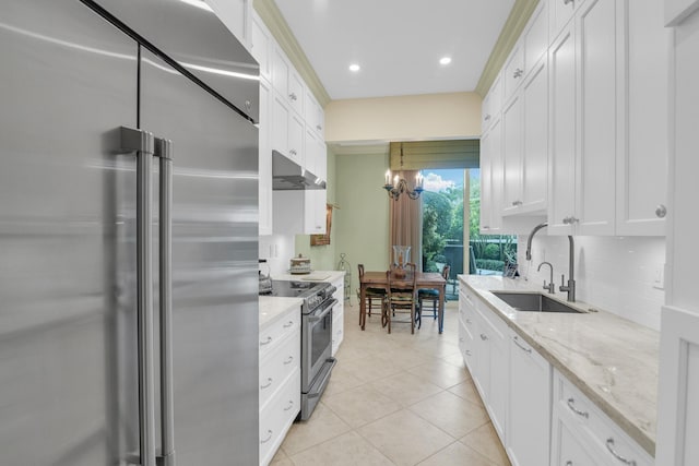 kitchen featuring light stone countertops, appliances with stainless steel finishes, sink, a notable chandelier, and white cabinetry