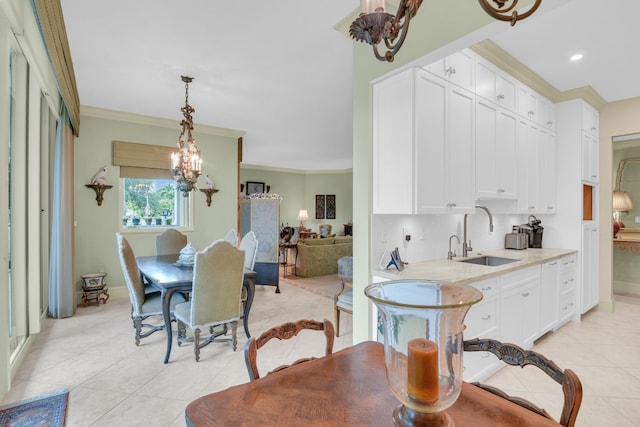 tiled dining room featuring crown molding, sink, and a chandelier