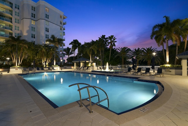 pool at dusk featuring a patio