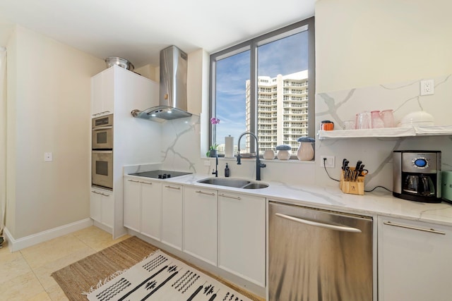 kitchen featuring sink, white cabinetry, stainless steel appliances, light stone counters, and wall chimney exhaust hood