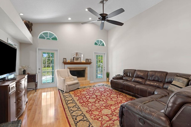 living room with a healthy amount of sunlight, ceiling fan, high vaulted ceiling, and light hardwood / wood-style floors