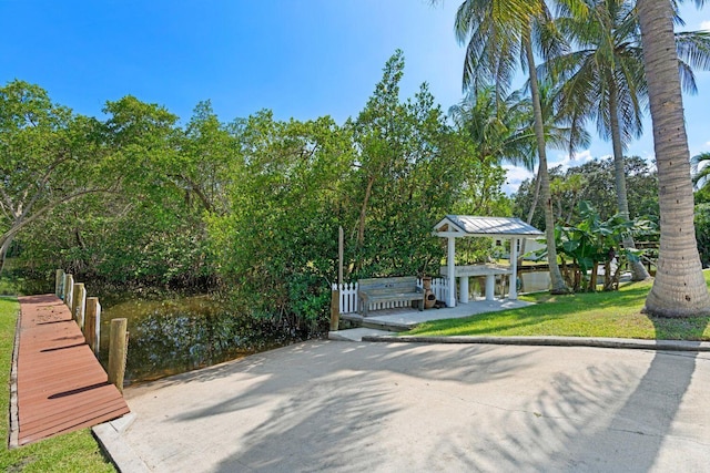 view of home's community with a yard, a water view, and a dock