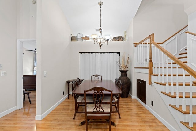 dining room featuring ceiling fan with notable chandelier, light wood-type flooring, and vaulted ceiling