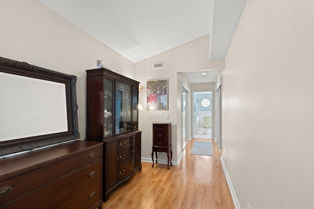 hallway featuring light hardwood / wood-style flooring and lofted ceiling