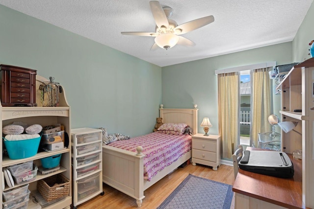 bedroom with ceiling fan, a textured ceiling, and light wood-type flooring