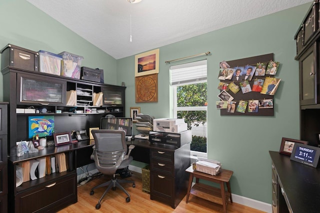 office area with a textured ceiling, light hardwood / wood-style flooring, and lofted ceiling