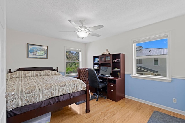 bedroom featuring ceiling fan, light hardwood / wood-style floors, and a textured ceiling